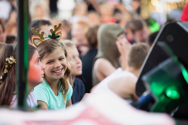 Student smiling at Christmas liturgy with reindeer antler headband